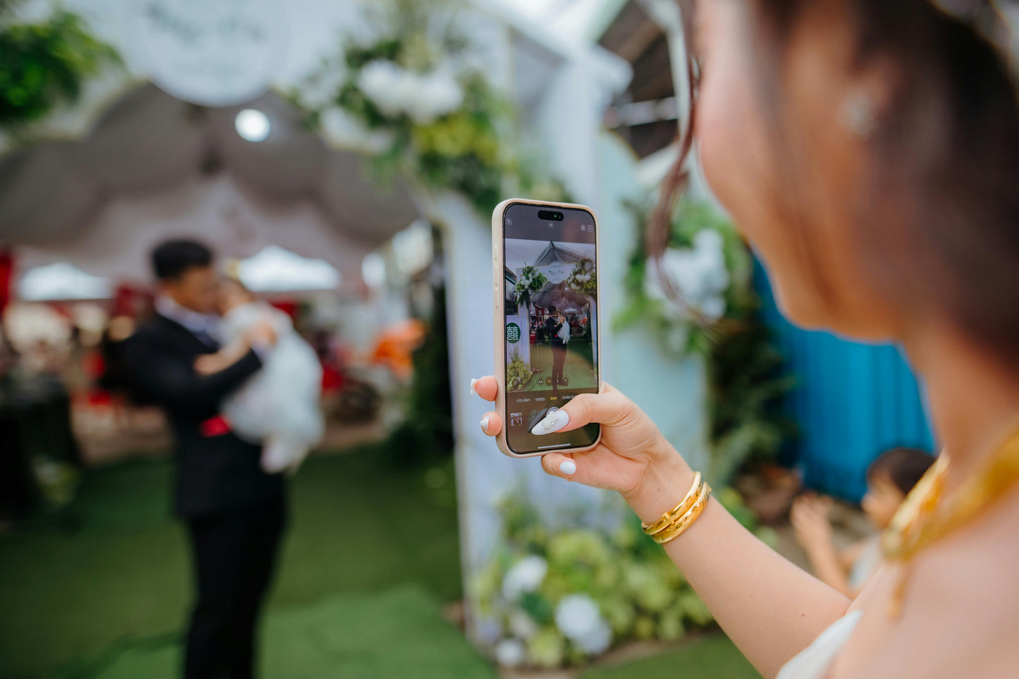 Person taking a video with a phone at an outdoor wedding.